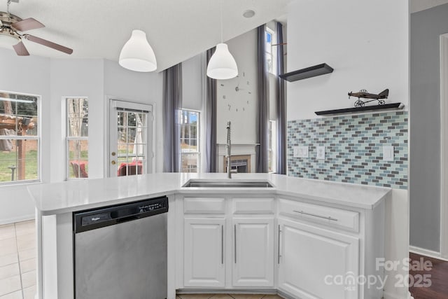 kitchen with white cabinets, dishwasher, light countertops, and a sink