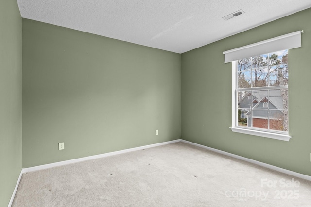 spare room featuring carpet, visible vents, and baseboards