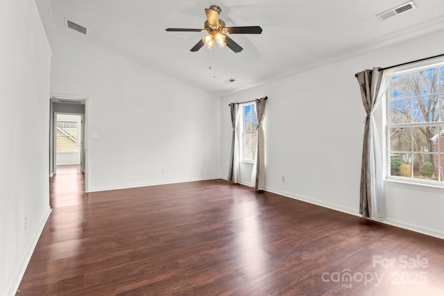 empty room featuring dark wood-type flooring, visible vents, lofted ceiling, and ceiling fan