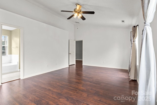 empty room featuring visible vents, ceiling fan, baseboards, vaulted ceiling, and wood finished floors