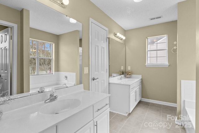 bathroom with tile patterned flooring, a garden tub, visible vents, and a sink