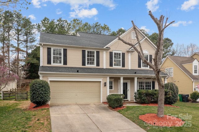 traditional-style house with a front yard, fence, roof with shingles, an attached garage, and concrete driveway