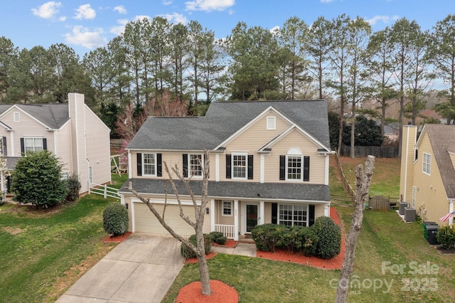 traditional-style home with a front yard, fence, and driveway