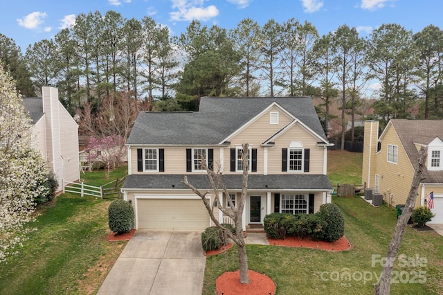 traditional-style home with a front yard, fence, driveway, central AC, and a garage