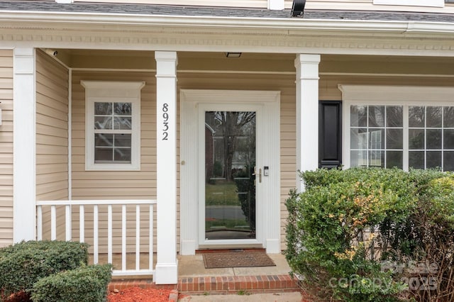 property entrance with covered porch and a shingled roof