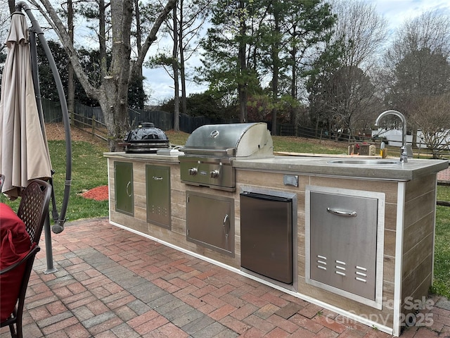 view of patio with grilling area, an outdoor kitchen, a fenced backyard, and a sink