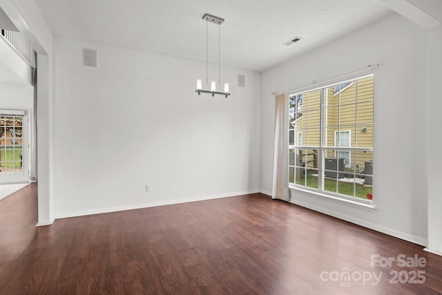 unfurnished dining area featuring wood finished floors, plenty of natural light, a chandelier, and a textured ceiling