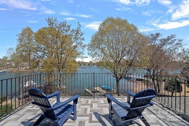 view of patio featuring a water view and fence