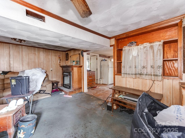 basement featuring wooden walls, a fireplace, and freestanding refrigerator