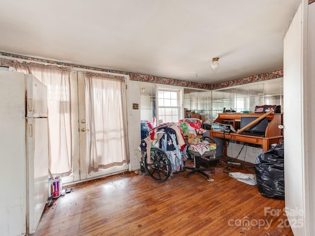 bedroom featuring a garage, wood finished floors, and freestanding refrigerator