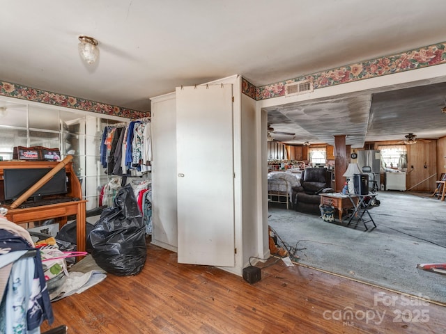 interior space with a ceiling fan, wood finished floors, and visible vents