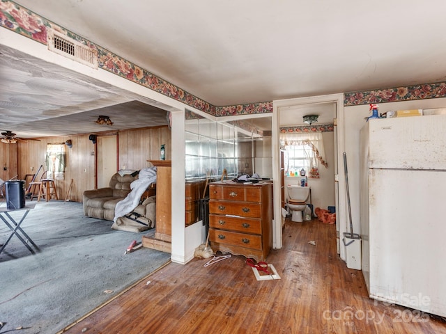 interior space featuring wooden walls, freestanding refrigerator, and hardwood / wood-style flooring