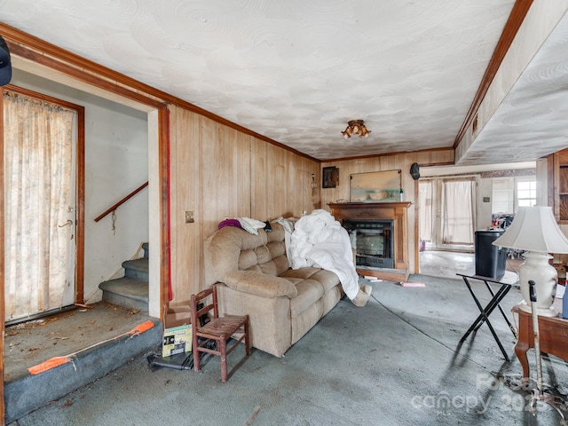 living room featuring stairs, crown molding, wooden walls, and a fireplace