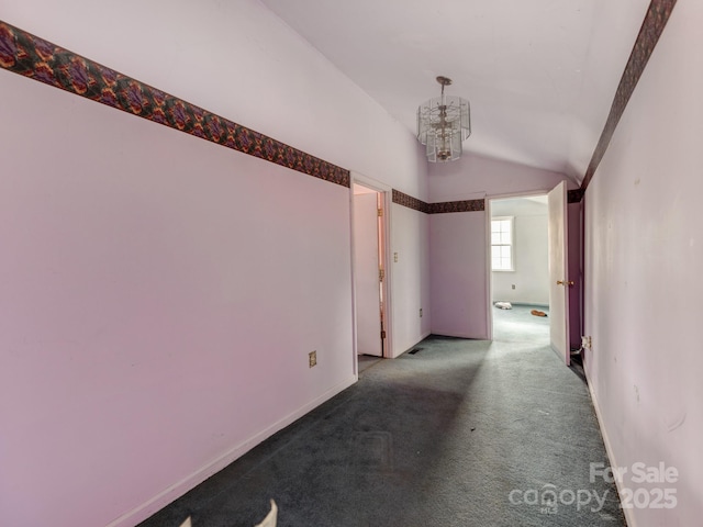 corridor with baseboards, carpet floors, a notable chandelier, and vaulted ceiling