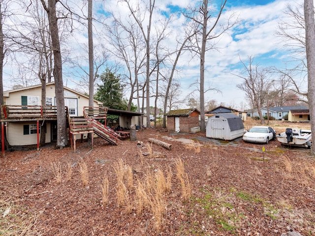 view of yard with an outbuilding, a shed, stairway, and a wooden deck