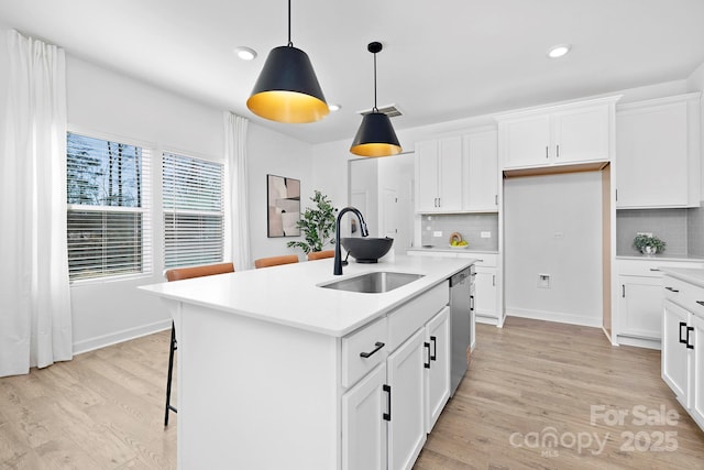 kitchen featuring light wood-type flooring, light countertops, a sink, and stainless steel dishwasher