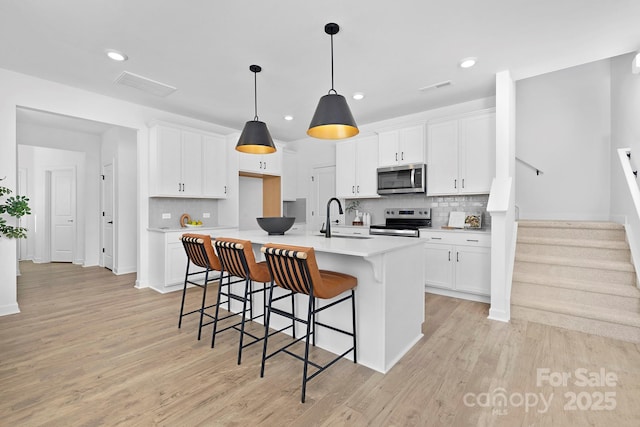 kitchen featuring a sink, visible vents, white cabinetry, light countertops, and appliances with stainless steel finishes