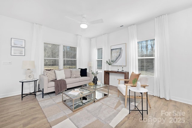 living area with plenty of natural light, wood finished floors, and baseboards