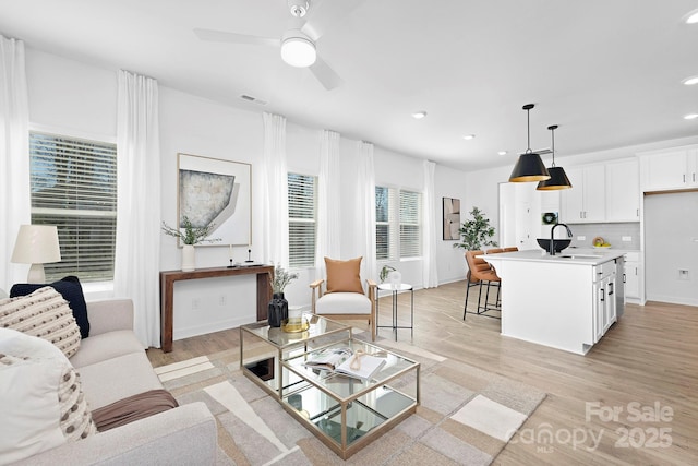 living area with light wood-type flooring, ceiling fan, baseboards, and recessed lighting