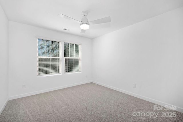 carpeted spare room with a ceiling fan, visible vents, and baseboards