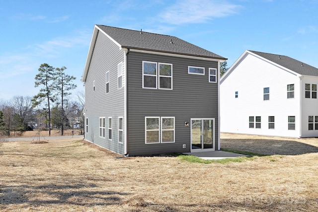 rear view of house featuring a patio area, a shingled roof, and a yard