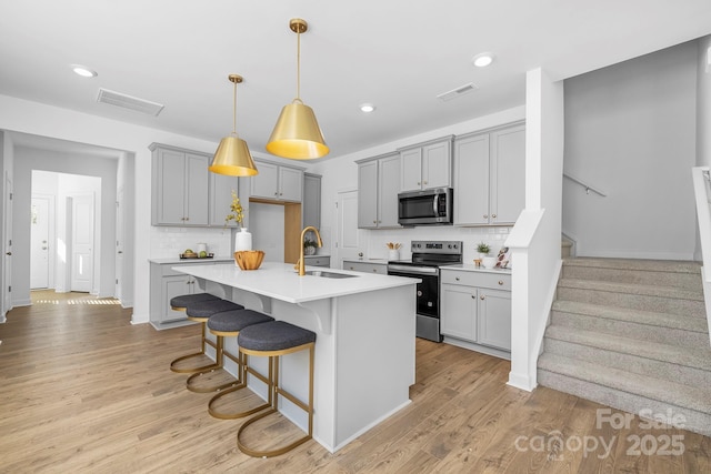 kitchen featuring appliances with stainless steel finishes, gray cabinetry, a sink, and visible vents