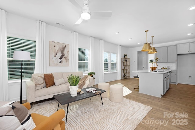 living room featuring baseboards, visible vents, recessed lighting, light wood-style floors, and a ceiling fan