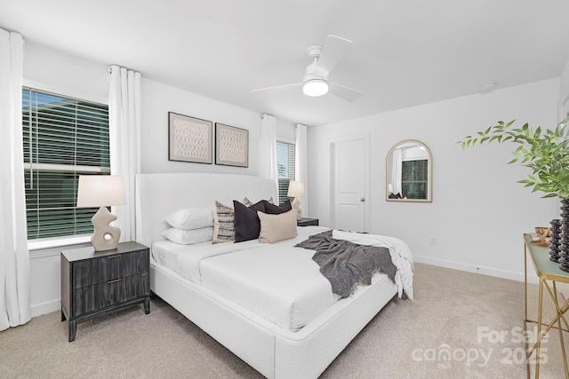 bedroom with a ceiling fan, baseboards, and light colored carpet