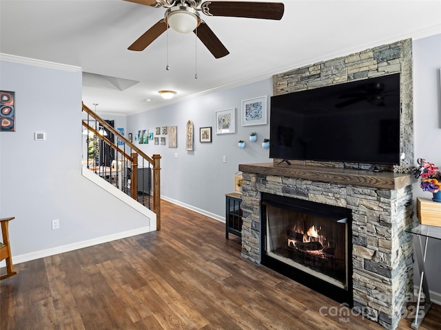 living area featuring a fireplace, wood finished floors, baseboards, stairway, and crown molding