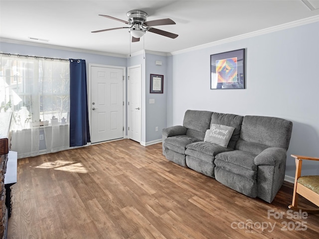 living room with baseboards, visible vents, a ceiling fan, ornamental molding, and wood finished floors