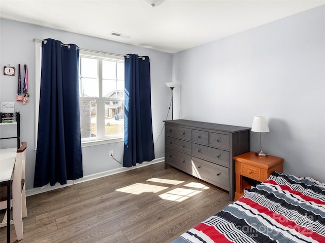 bedroom featuring baseboards, visible vents, and wood finished floors