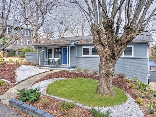 view of front of home featuring brick siding, a porch, and a front yard