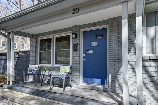 property entrance with covered porch and brick siding