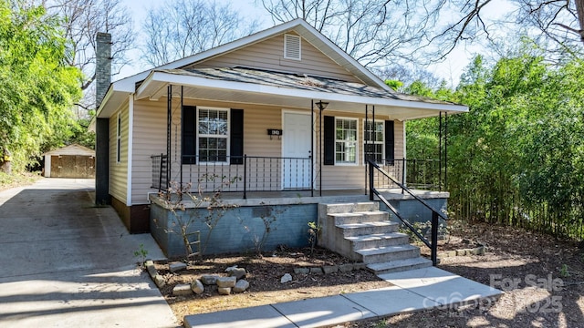 view of front of house featuring covered porch, driveway, crawl space, and an outbuilding