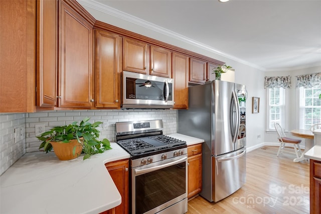 2050 Sunswept Ln, York, SC 29745 - kitchen featuring appliances with stainless steel finishes, brown cabinetry, light wood finished floors, ornamental molding, and backsplash