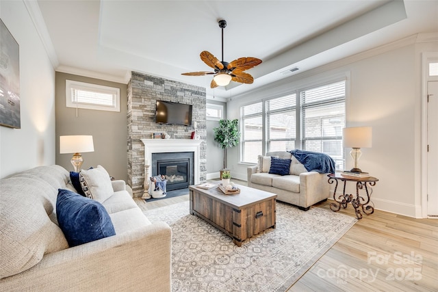333 Lifestyle Ct, Cramerton, NC 28056 - living area featuring a tray ceiling, ceiling fan, light wood-style floors, crown molding, and a stone fireplace