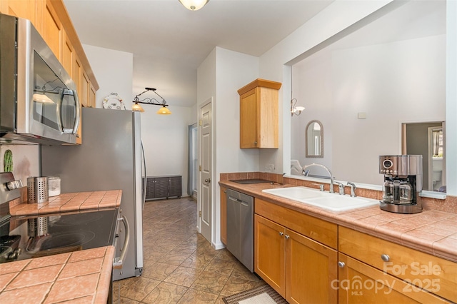 kitchen featuring tile countertops, stainless steel appliances, and a sink