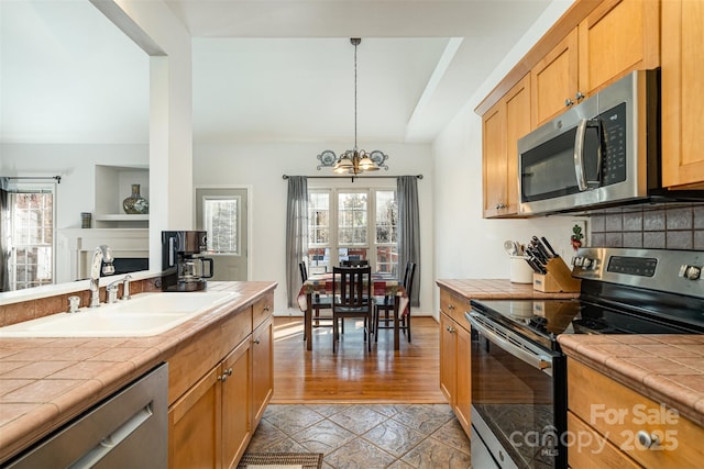 kitchen featuring an inviting chandelier, tile countertops, appliances with stainless steel finishes, and a sink