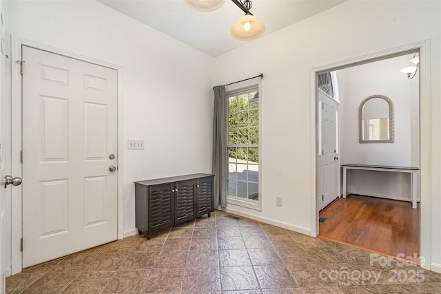 foyer featuring baseboards and stone finish floor