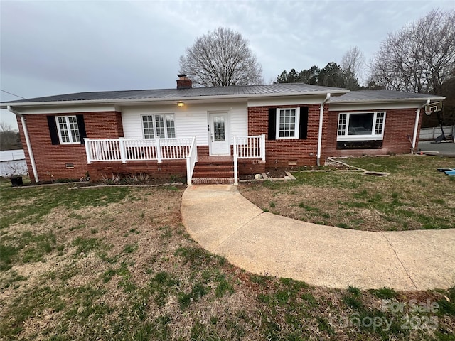 ranch-style home with brick siding, a front lawn, a chimney, metal roof, and crawl space