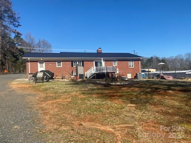 back of house featuring cooling unit, brick siding, and a chimney