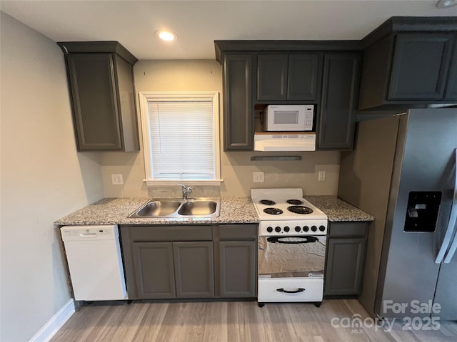 kitchen featuring white appliances, range hood, light wood finished floors, a sink, and light countertops