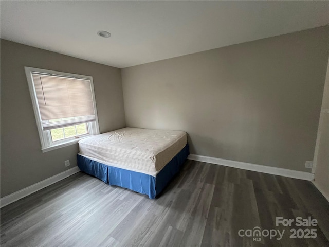 unfurnished bedroom with dark wood-style floors and baseboards