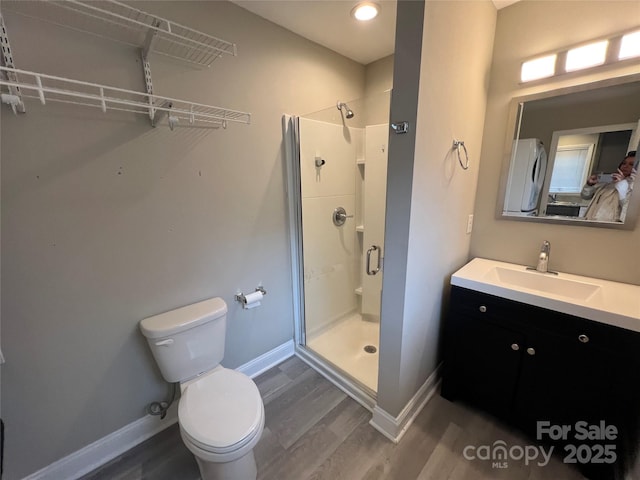 full bathroom featuring toilet, wood finished floors, a stall shower, and baseboards