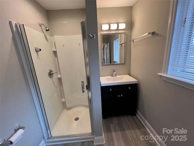 bathroom with vanity, a shower stall, wood finished floors, and baseboards