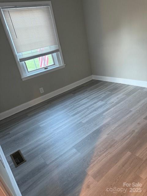 empty room with visible vents, baseboards, and wood finished floors