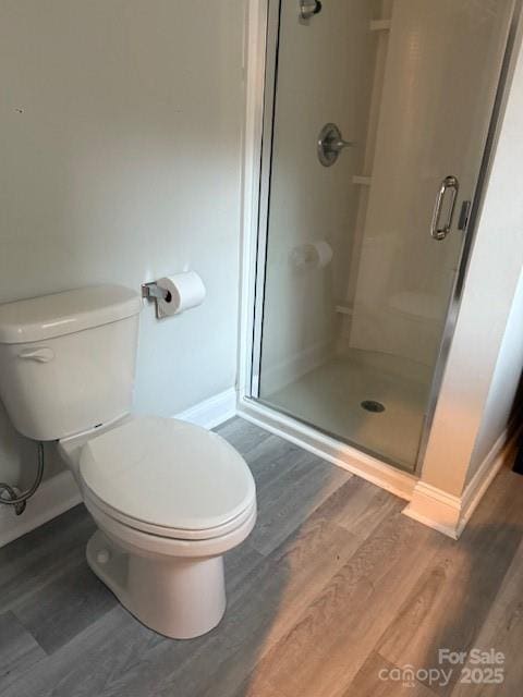 full bathroom featuring a stall shower, baseboards, toilet, and wood finished floors