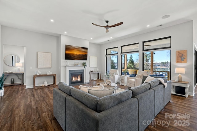 living room with a fireplace with flush hearth, recessed lighting, visible vents, and dark wood-style floors