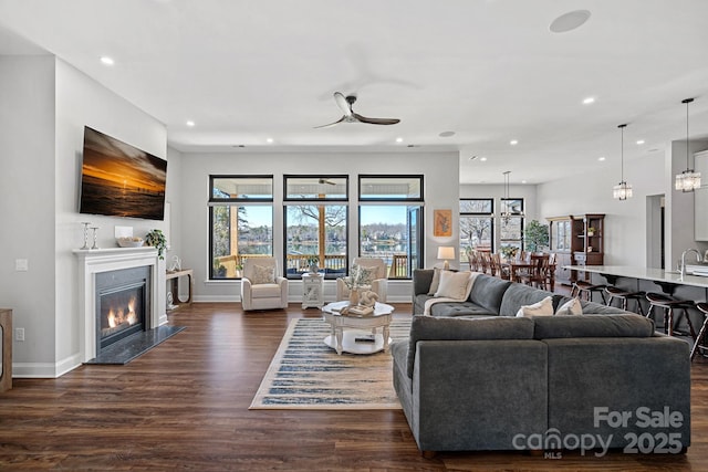 living area featuring dark wood-style flooring, recessed lighting, a high end fireplace, and a healthy amount of sunlight