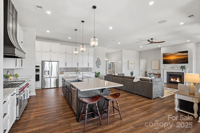 kitchen featuring stainless steel appliances, dark wood finished floors, visible vents, and a sink